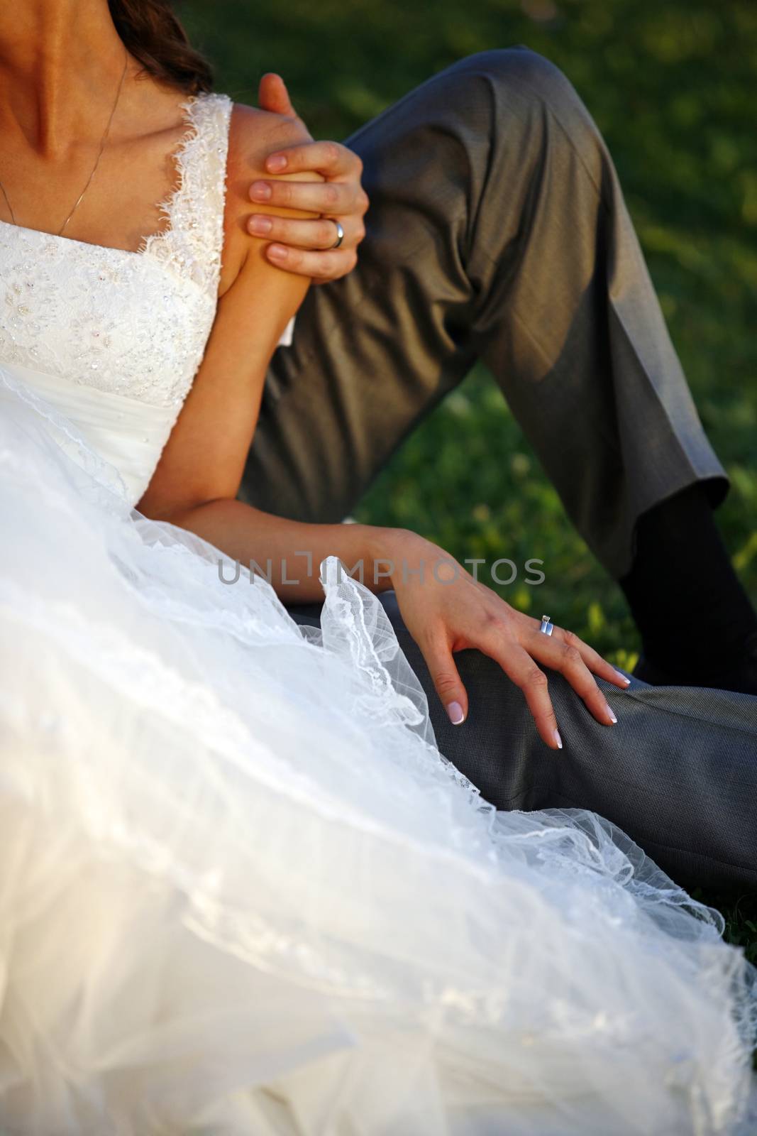 The groom and the bride sit on a grass