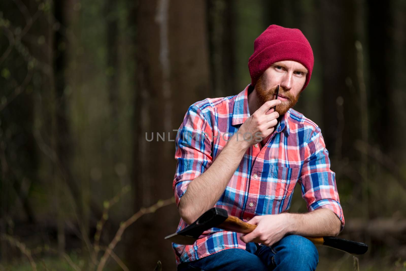 a forester with an ax in the forest combs his beard