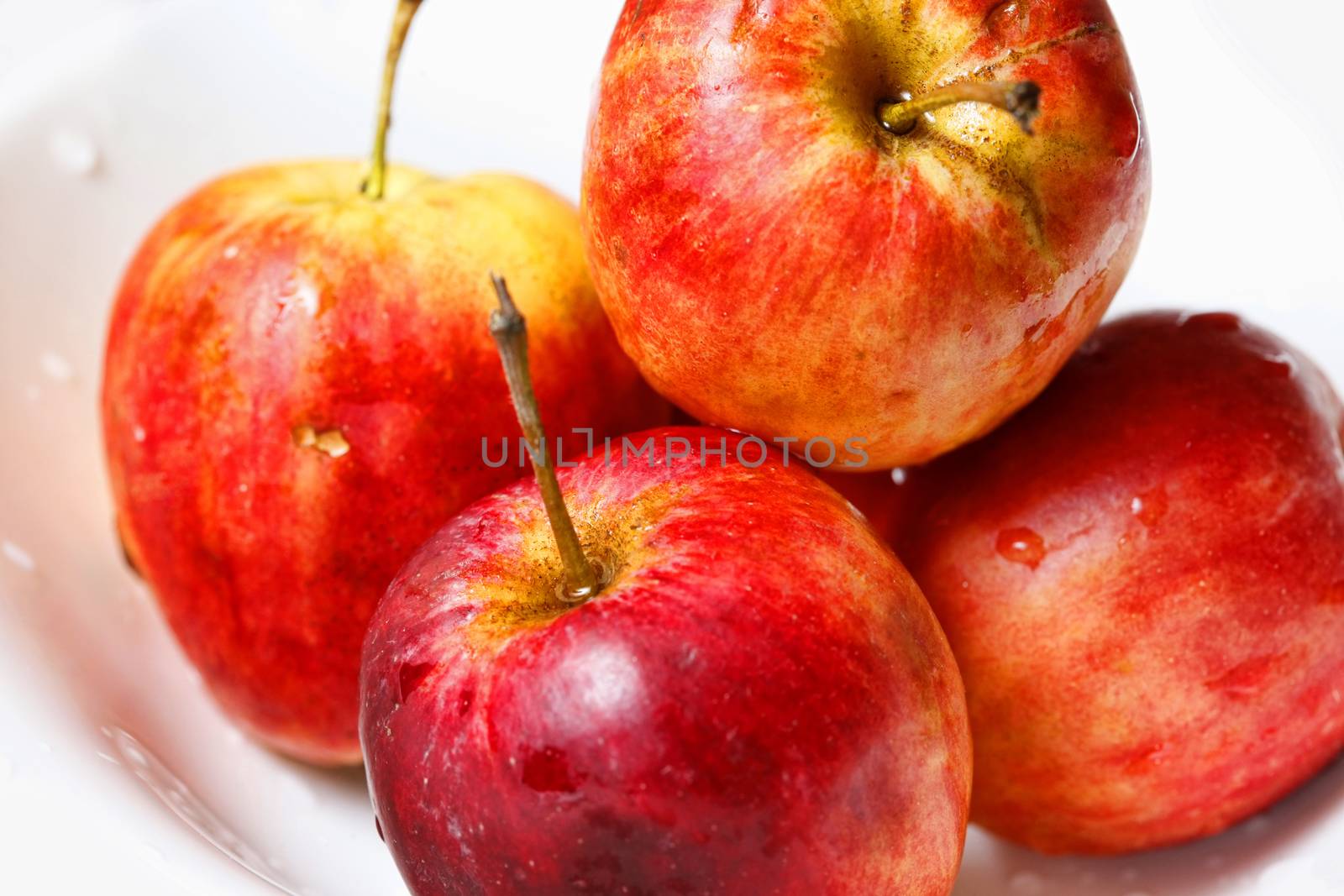 Red apples in drops close-up on a white background