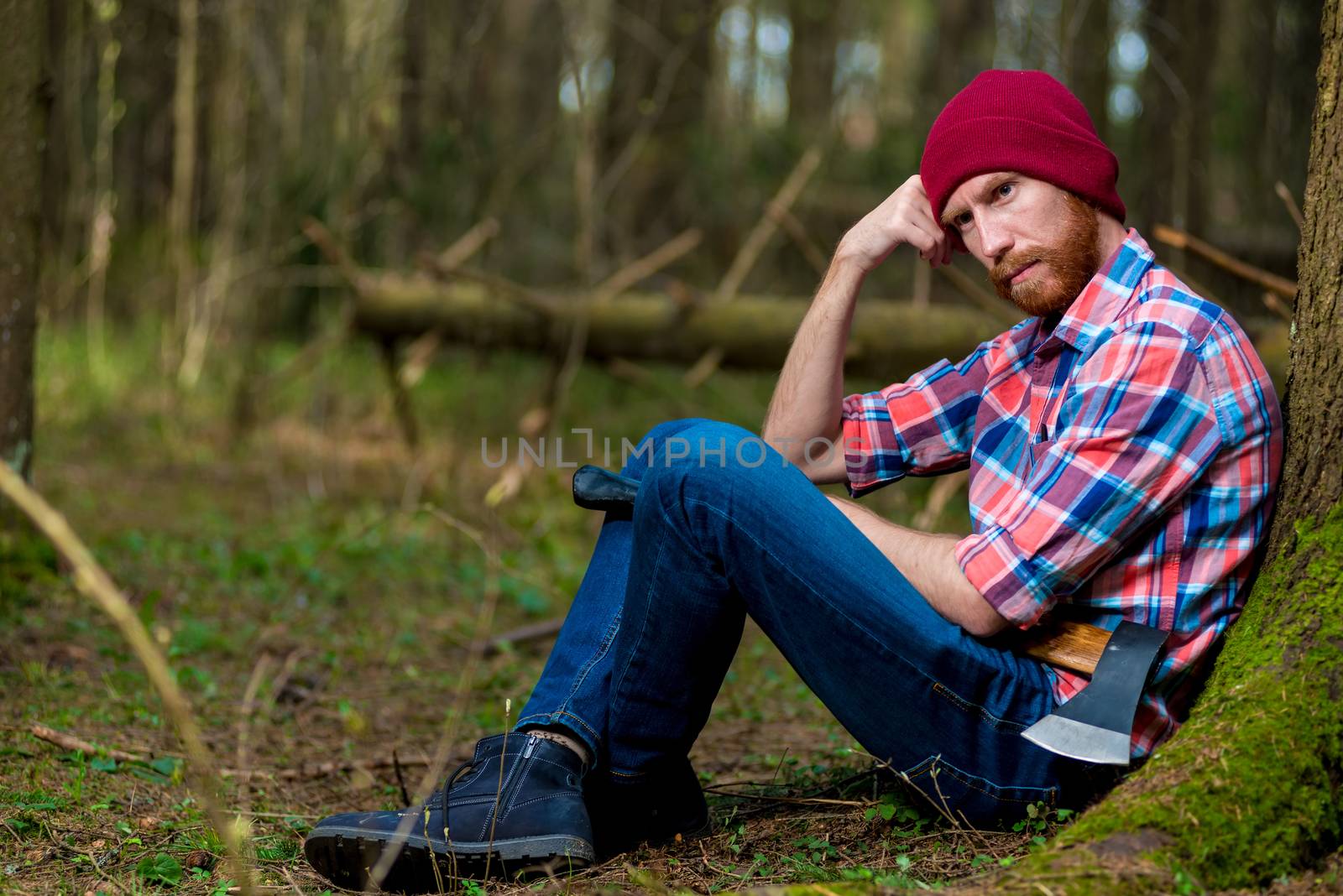 pensive bearded lumberjack on vacation near a tree in the forest by kosmsos111