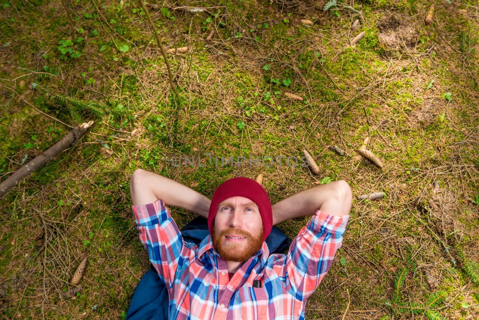 forester resting in the forest, lying on the ground surrounded by cones