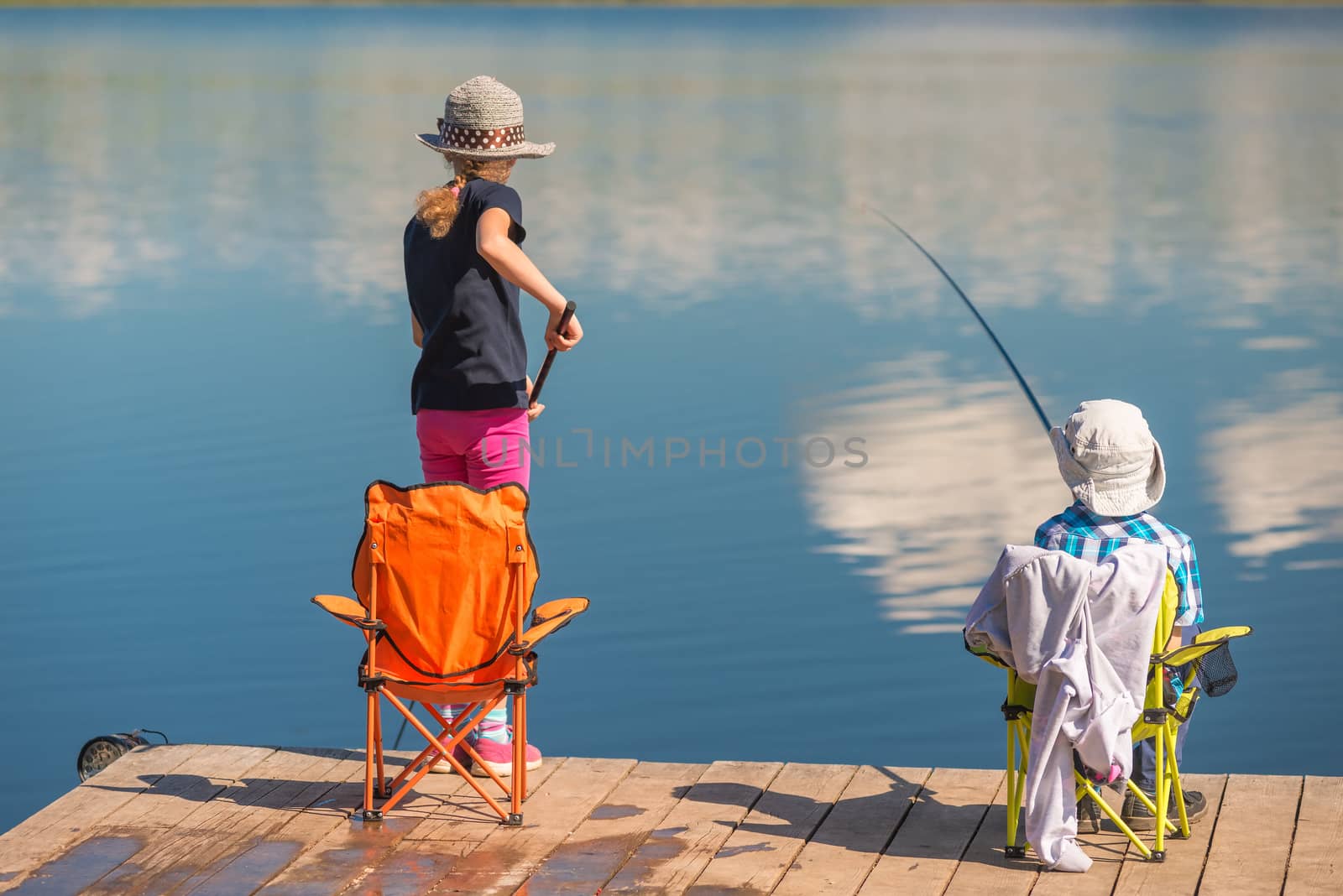 brother and sister are fishing on a wooden pier without adults by kosmsos111