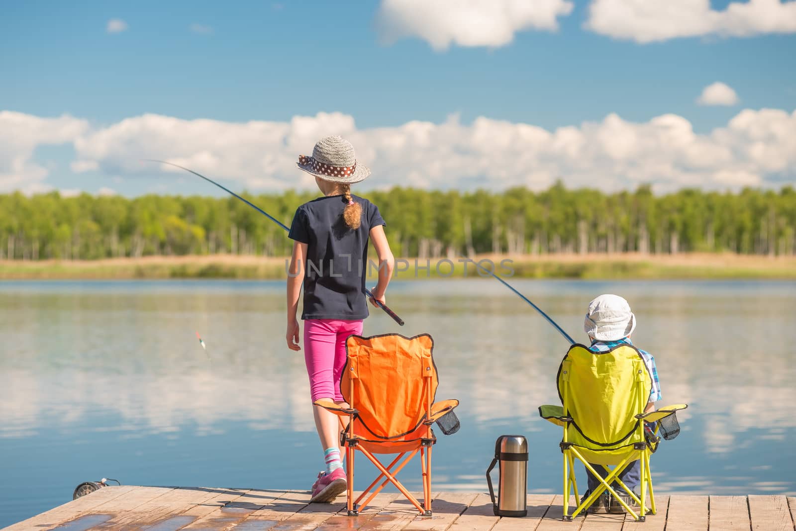 a girl and a boy spend time on the pier, children with fishing rods are fishing