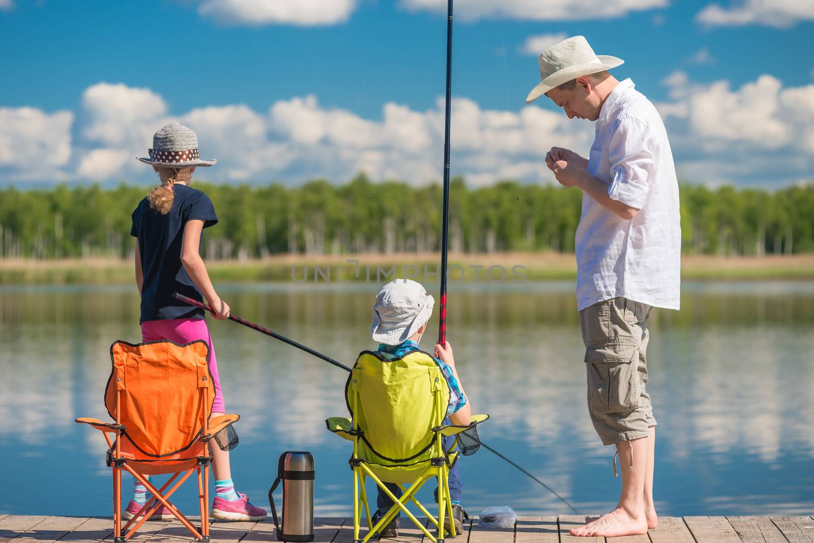 father teaches his children to fish on a fishing pole at the pie by kosmsos111