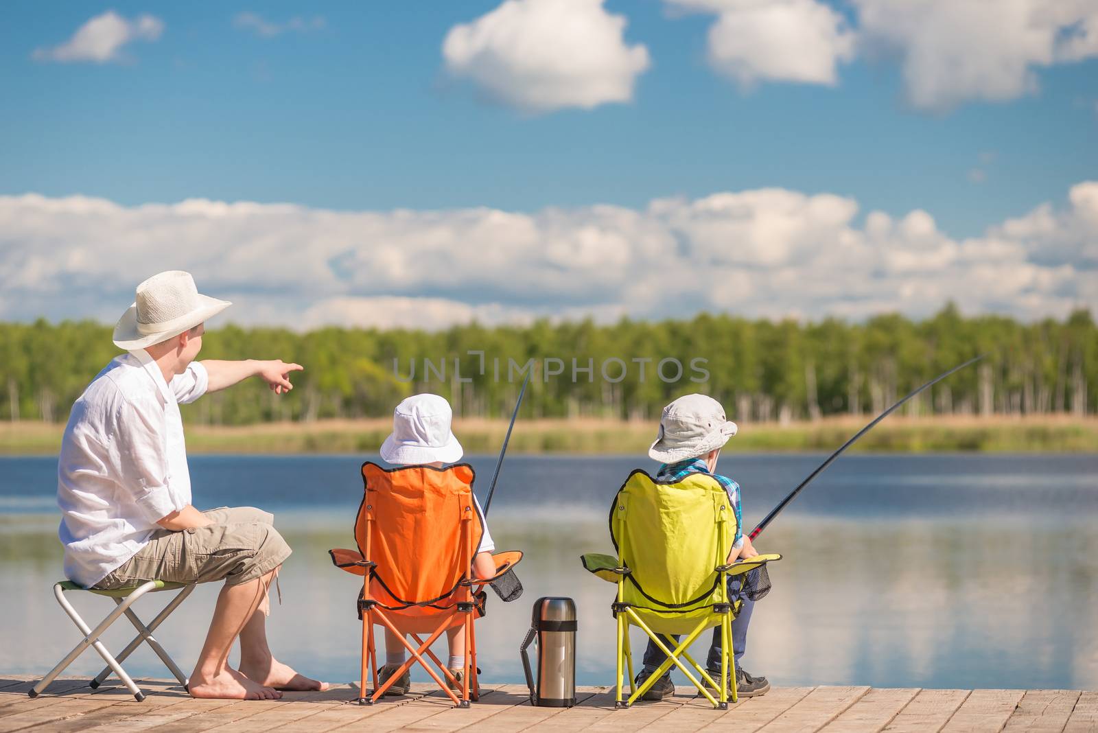 father shows his children the place of biting fish on the lake, fishing in the hobby