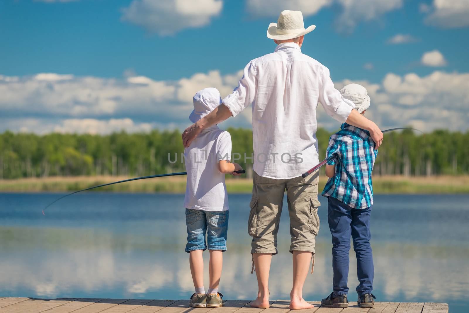 happy father with sons on a fishing trip on a beautiful lake