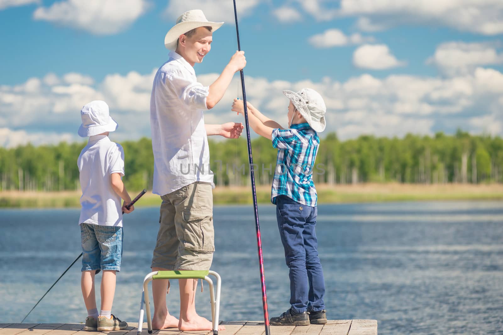 boys with his father on the pier while fishing, holding a weekend concept