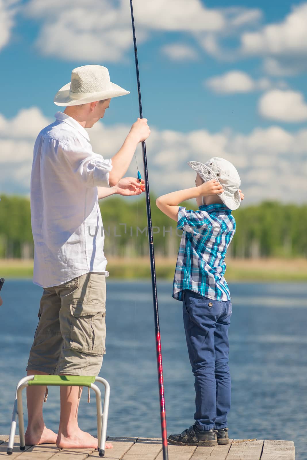 7-year-old son helps his father to fish in the lake by kosmsos111