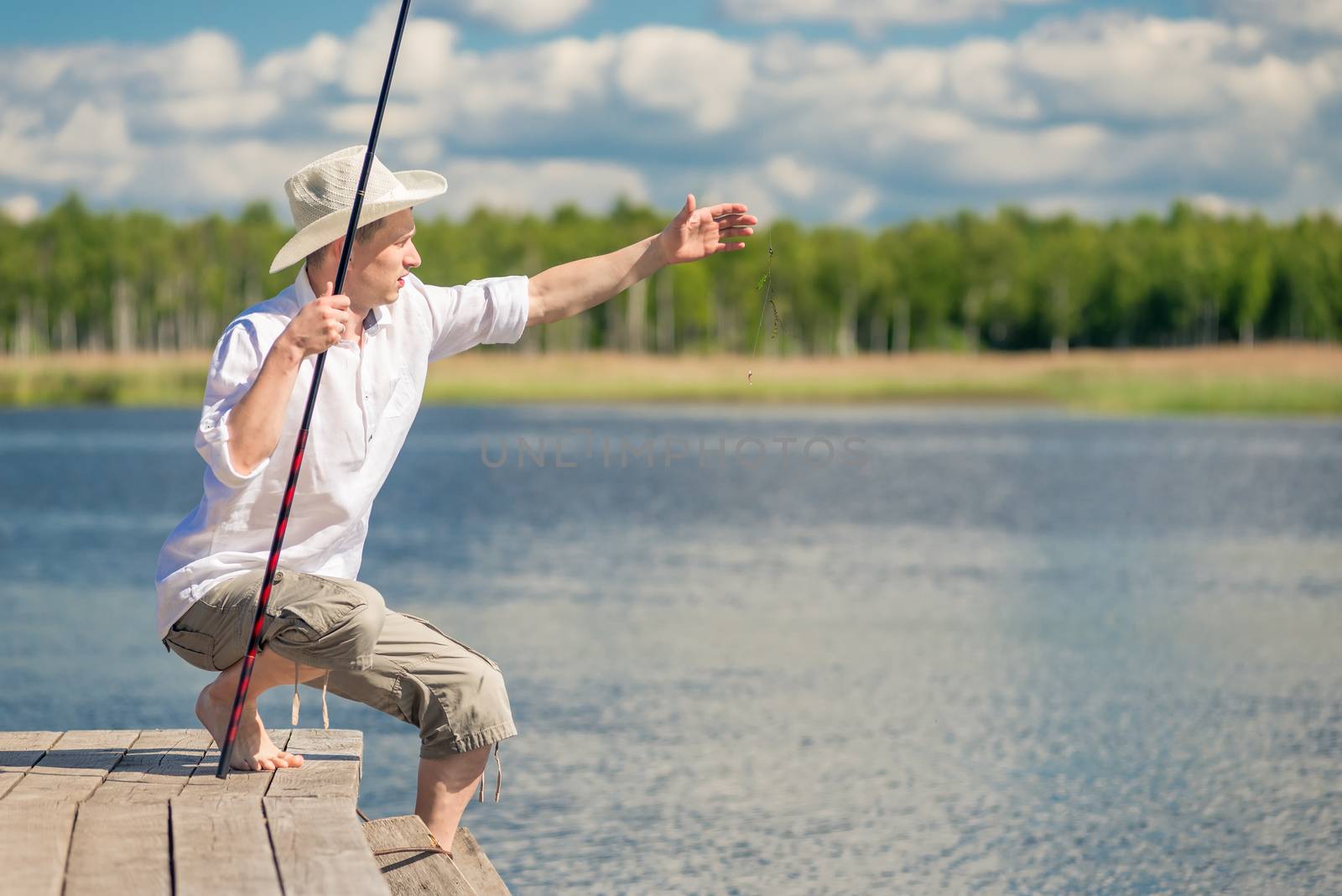 A fisherman in rural clothes on a fishing trip on a wooden pier