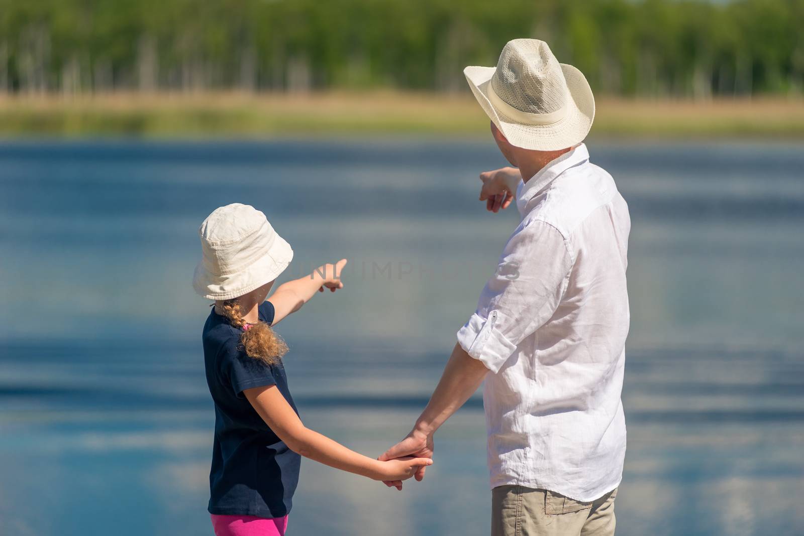 Father and daughter on the pier near the pond show water with a by kosmsos111