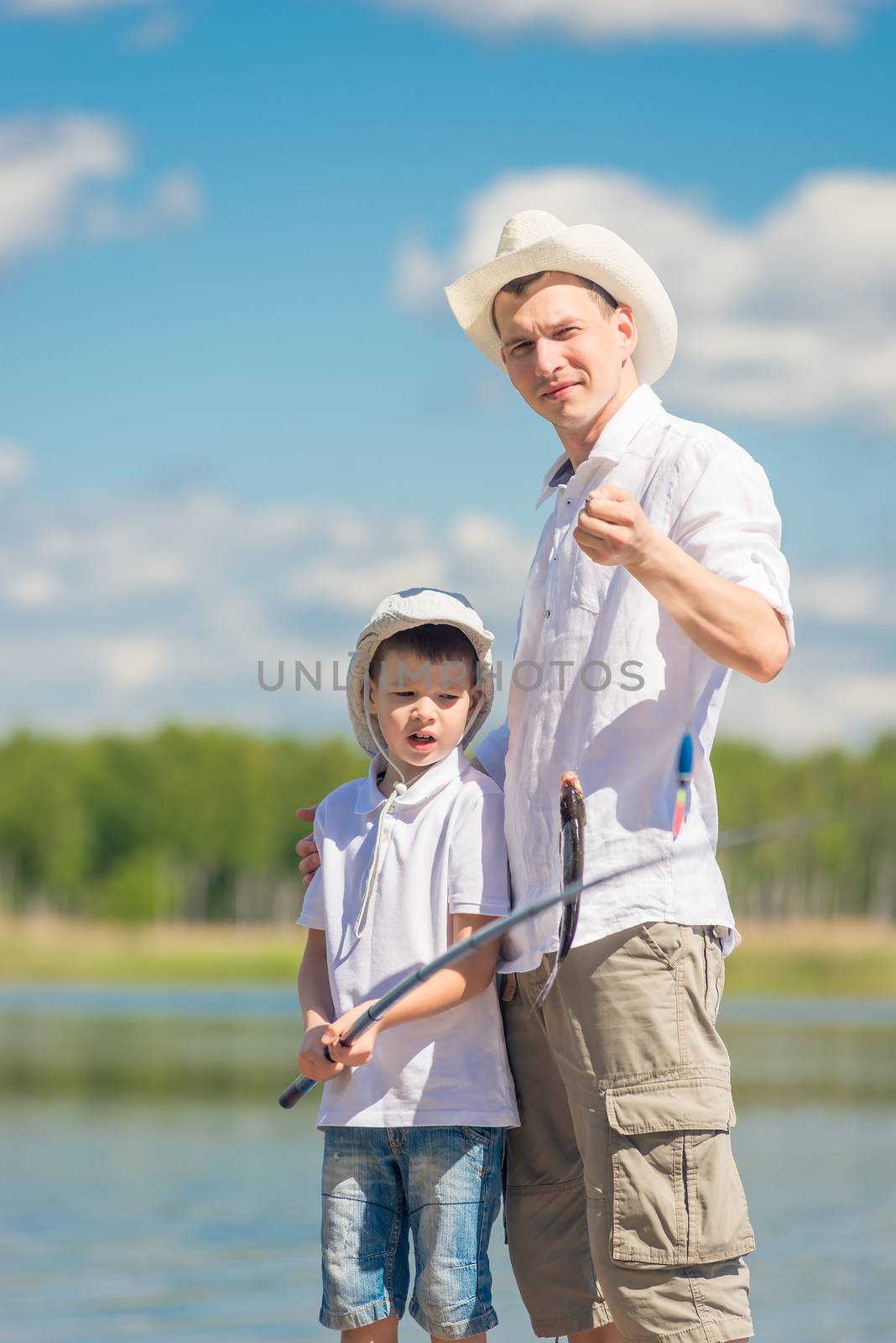 father and son on the pier with a big fish on the hook, fishing on the lake
