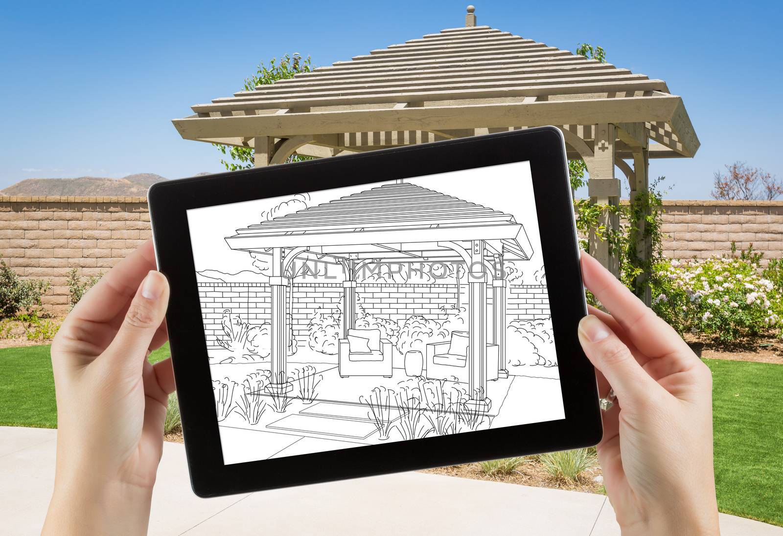 Female Hands Holding Computer Tablet with Drawing of Pergola on Screen, Photo Behind. by Feverpitched