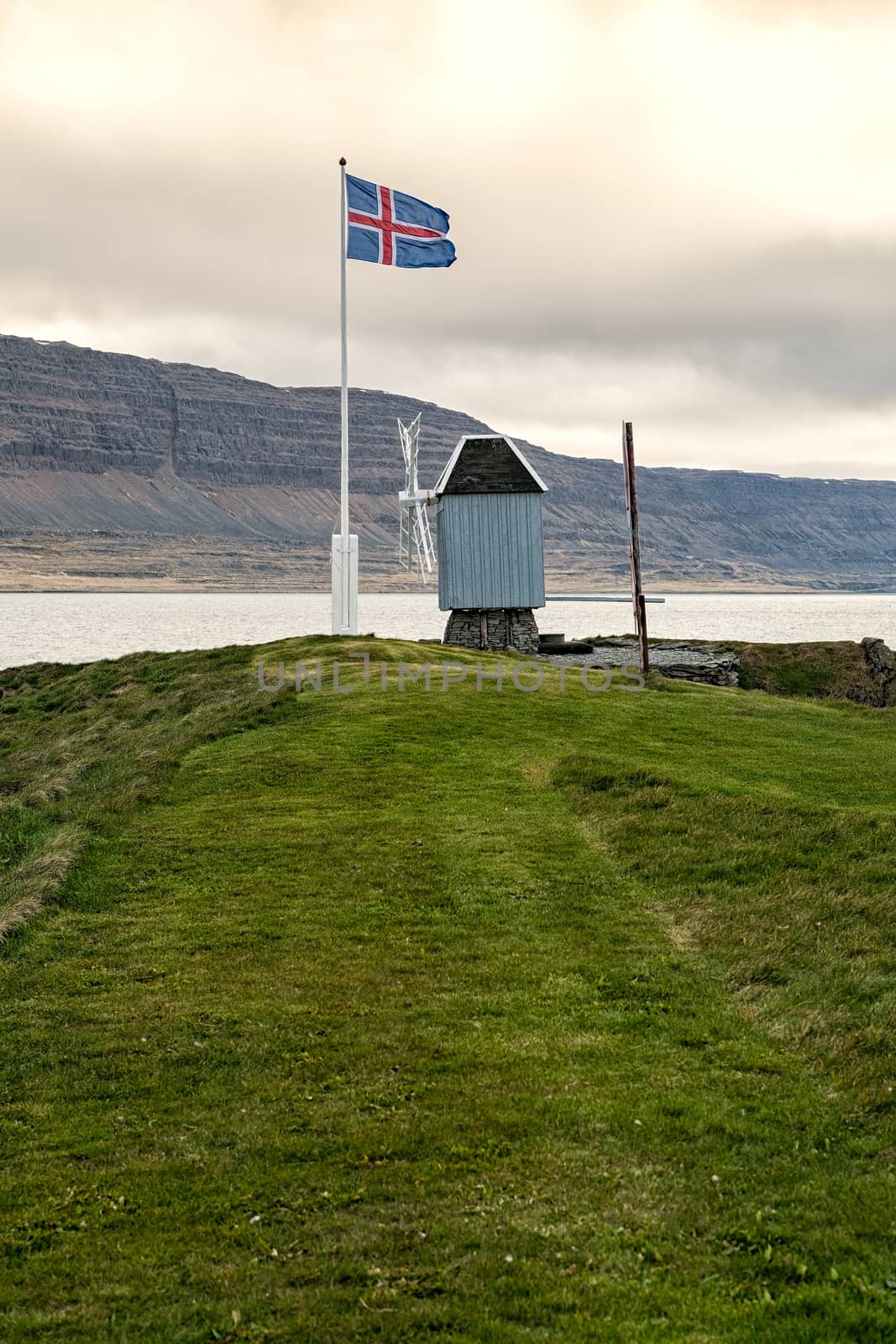 Windmill and Icelandic flag in Vigur island in a cloudy and windy day, Iceland