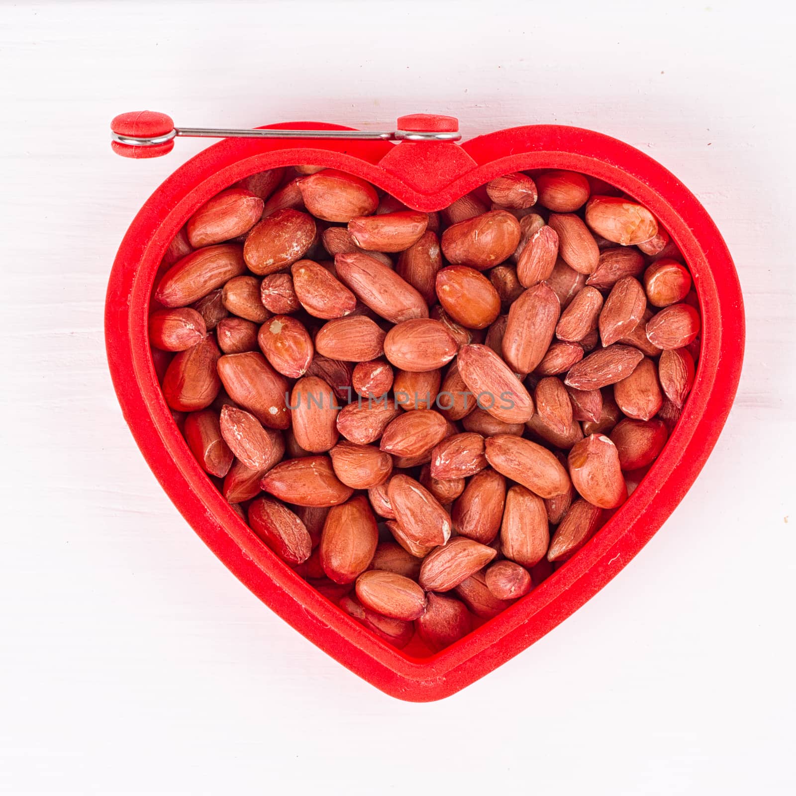 Raw peanuts in heart bowl. by victosha