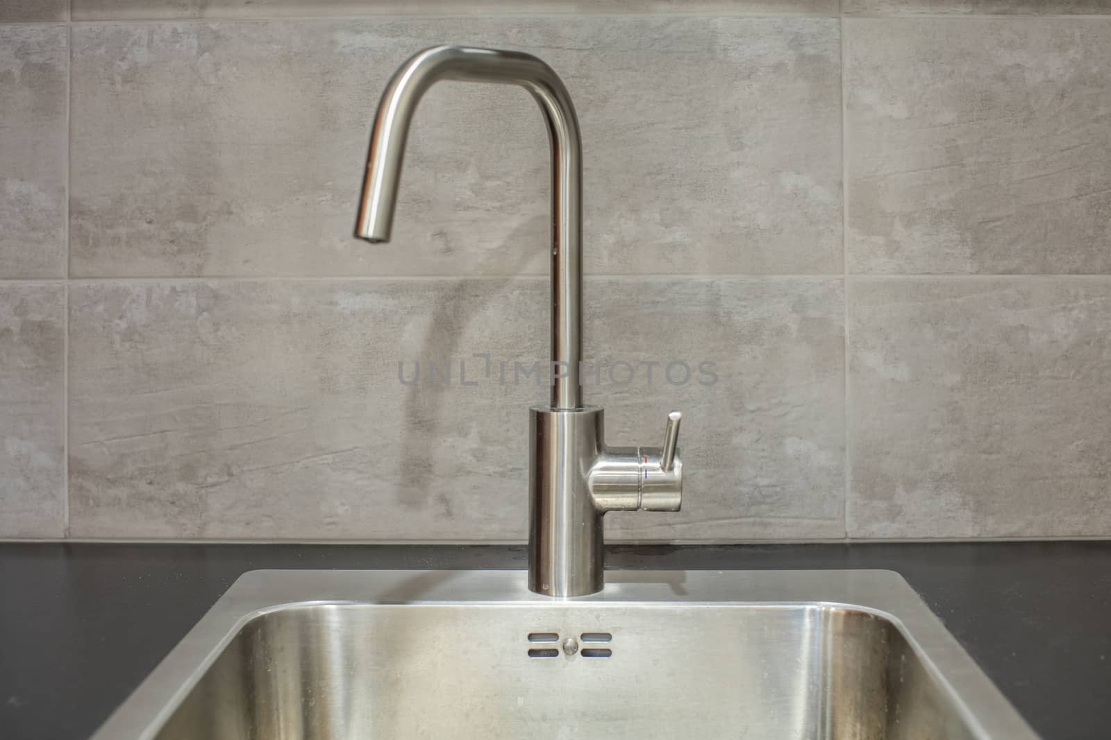 Close up of modern faucet and ceramic sink in kitchen