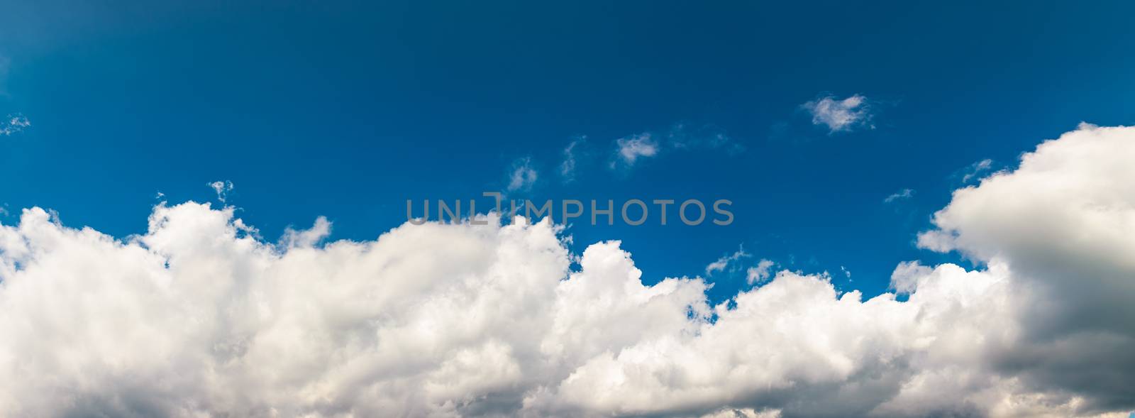 amazing cloud formations on a dark blue sky. beautiful side lit cloudscape panorama in summer