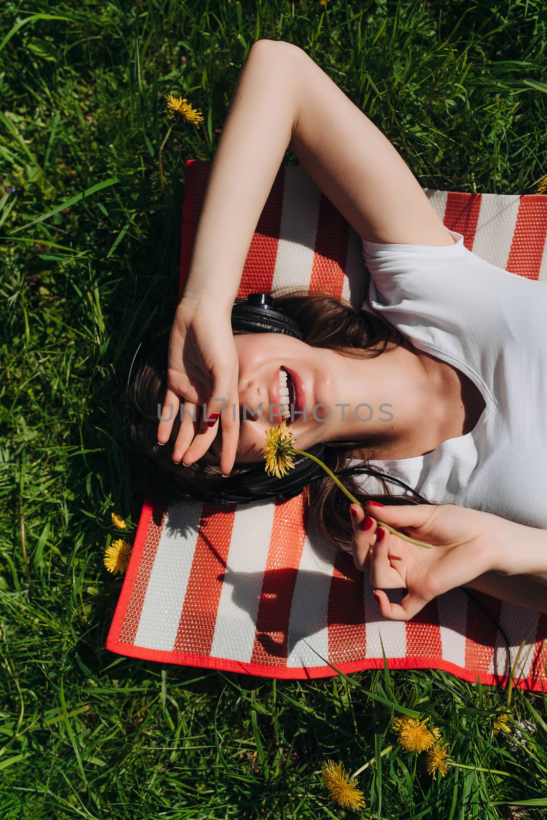 Young brunette woman with headphones listening to the music outdoors on sunny summer day