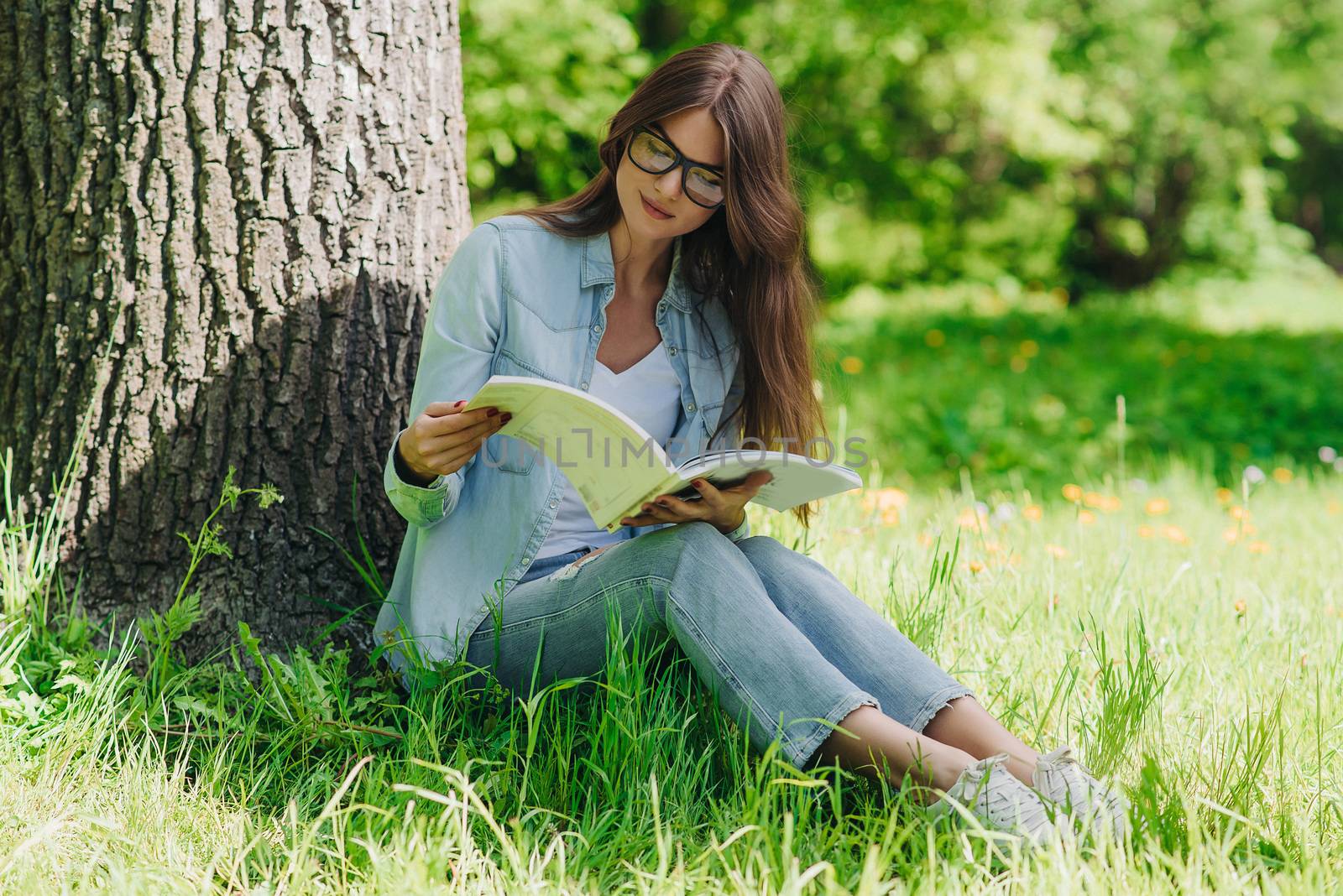 Woman reading a book in park by ALotOfPeople