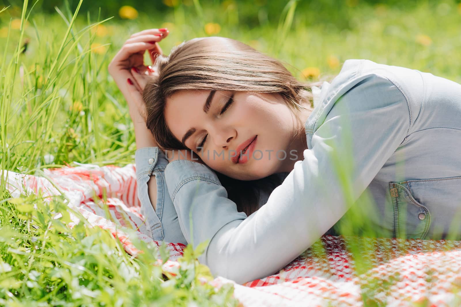 Beautiful young woman sleeping on fresh spring grass in park