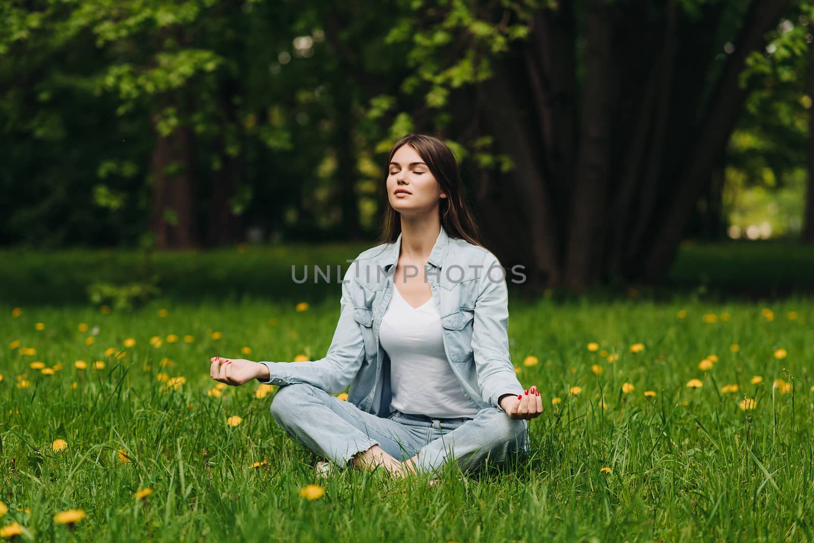 Beautiful young girl in casual clothes meditating in spring park