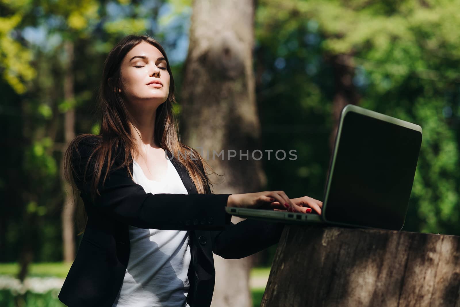 Beautiful business woman in suit using laptop computer in the park