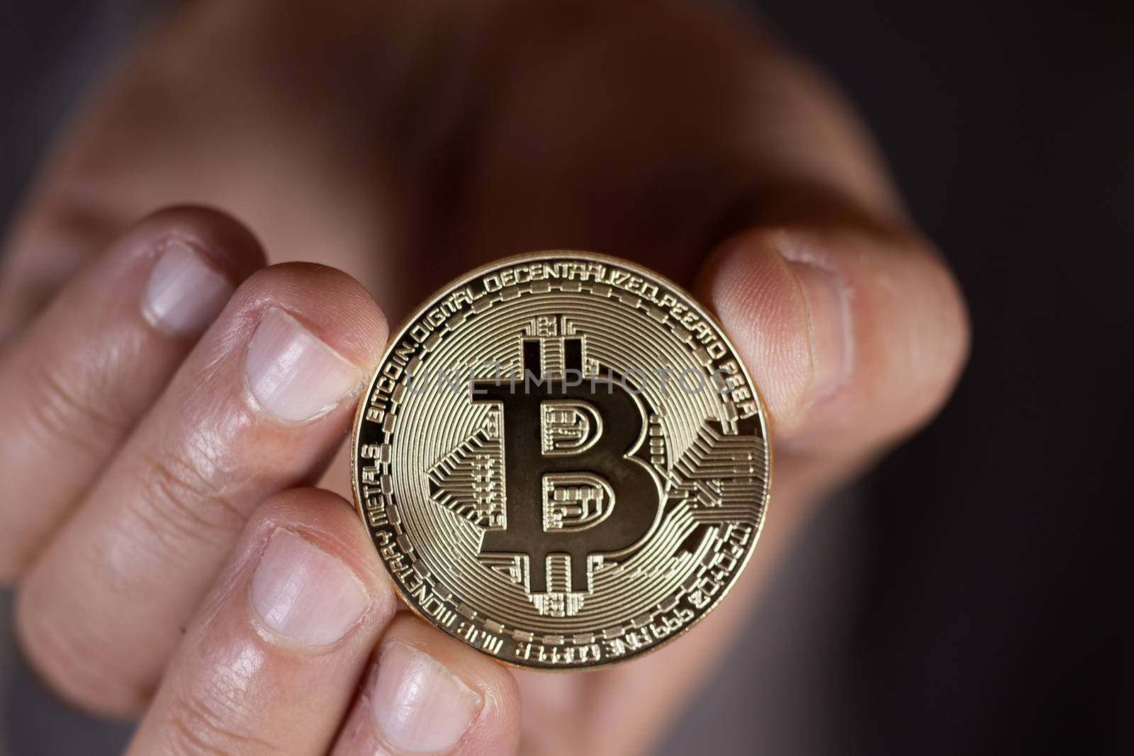 male hand holding a bitcoin, a digital crypto currency.