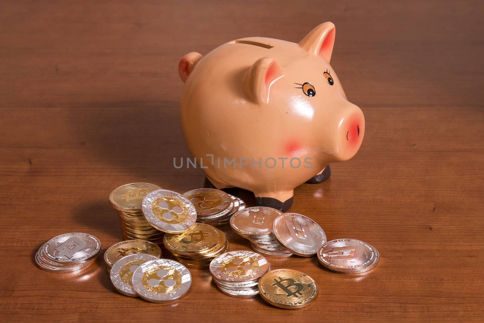 Piggy bank with several crypto currency coins on top of wooden table.