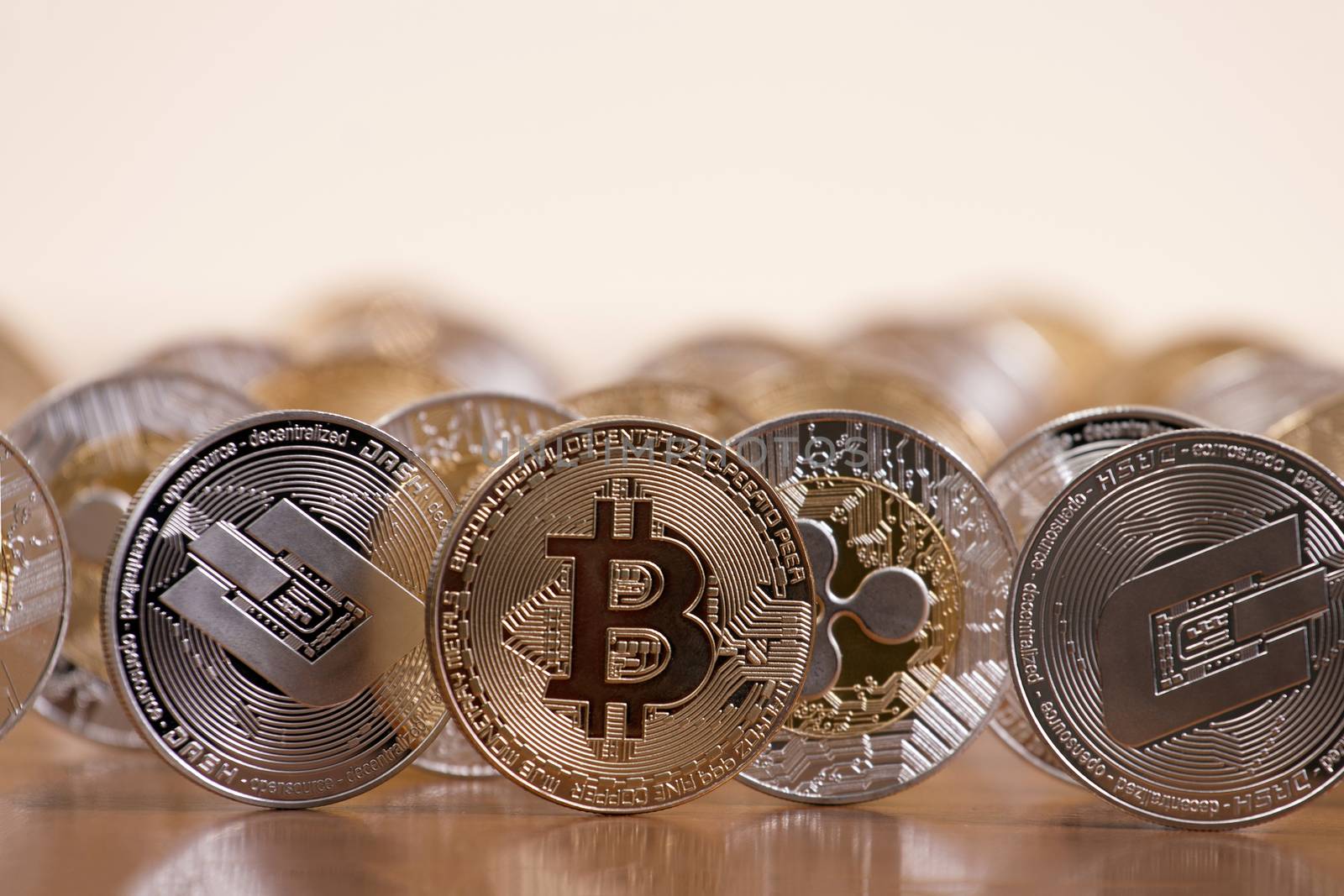 several aligned crypto currency coins on top of wooden table.