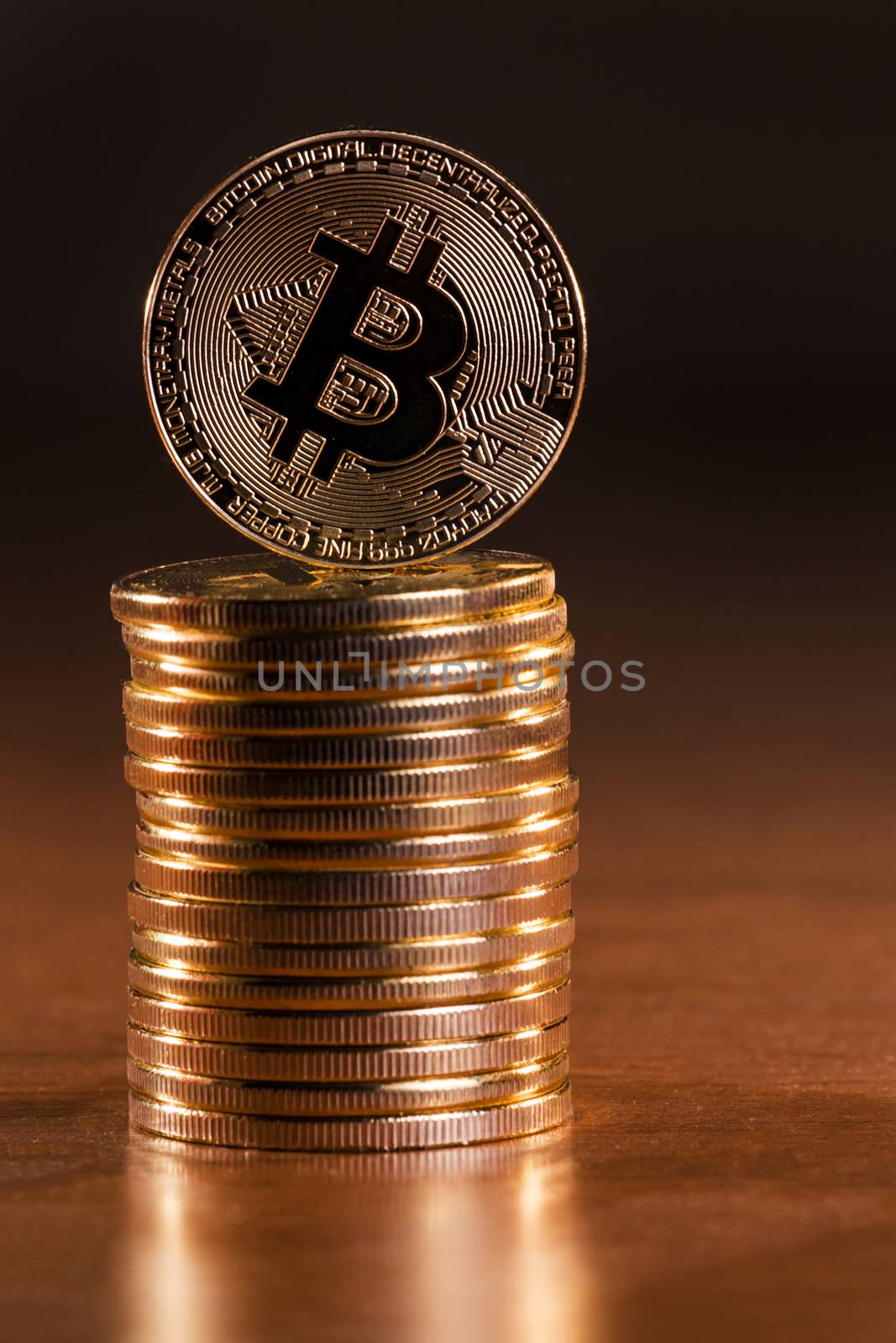 several golden bitcoins stacked on top of wooden table.