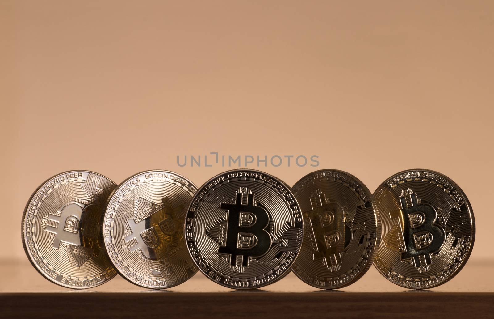 Shiny golden bitcoins on top of wooden table.
