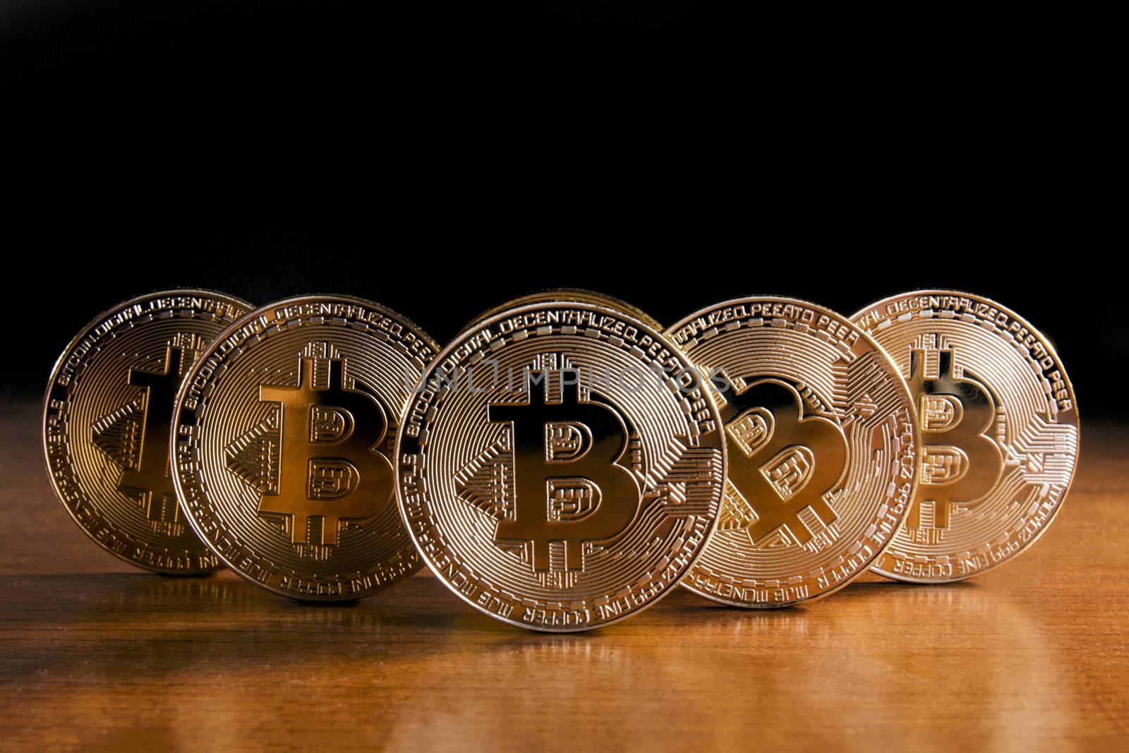 Shiny golden bitcoins on top of wooden table.