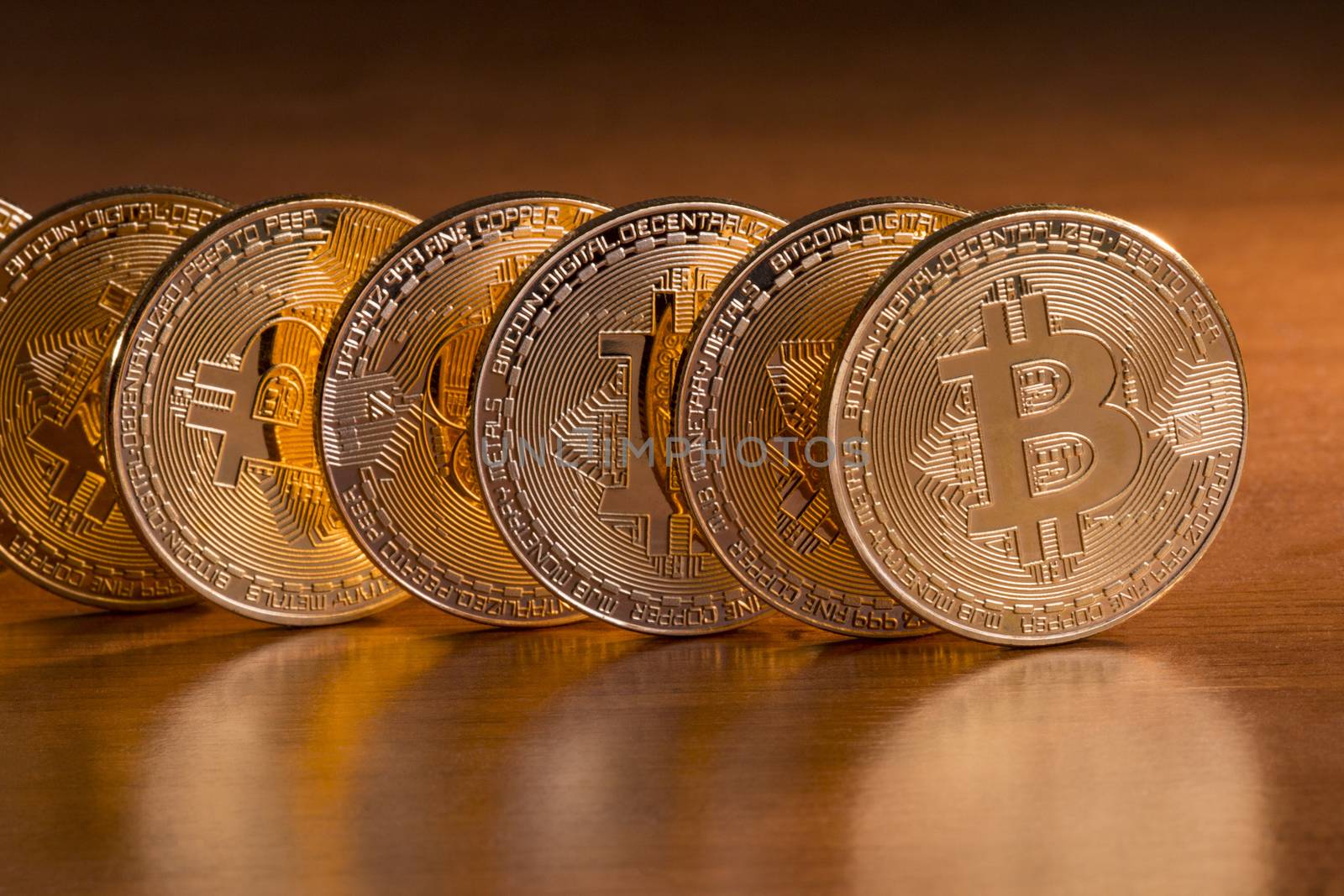 Shiny golden bitcoins on top of wooden table.