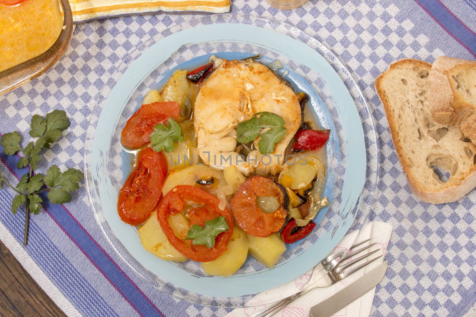 Traditional portuguese meal of fish with potatoes and tomato, made on the oven.