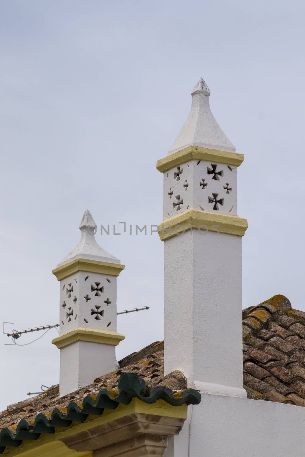 Typical chimneys on brown tile roofs in Portuguese architecture.