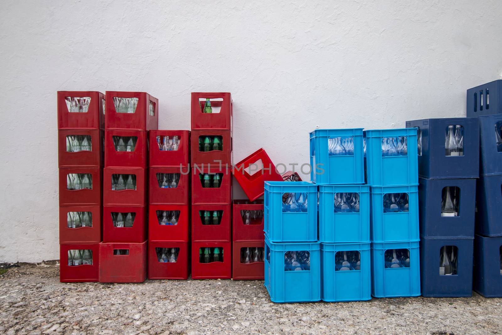 View of red and blue drink crates near a white wall.