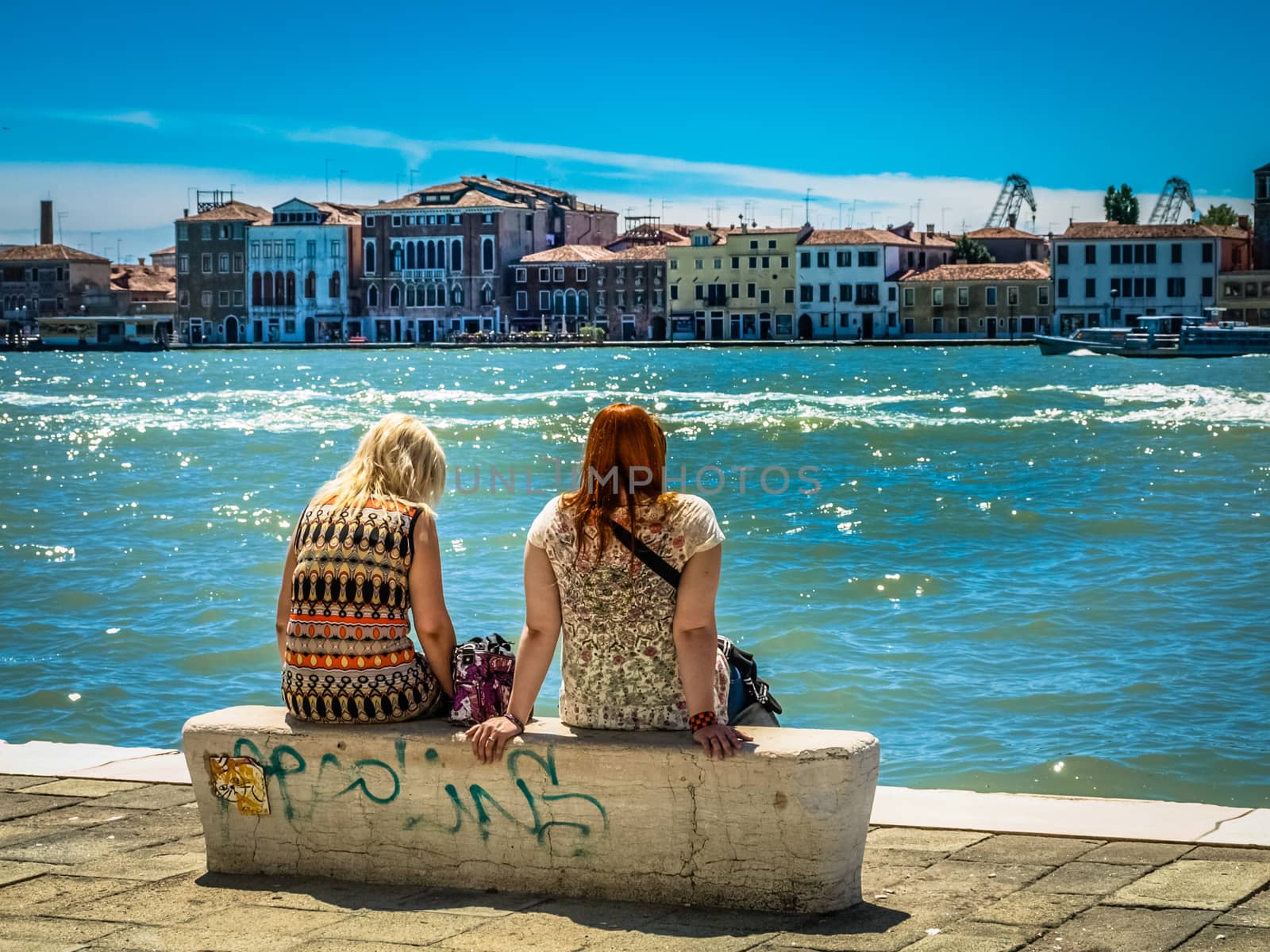 Two young girls sitting in the border of canal in Venice