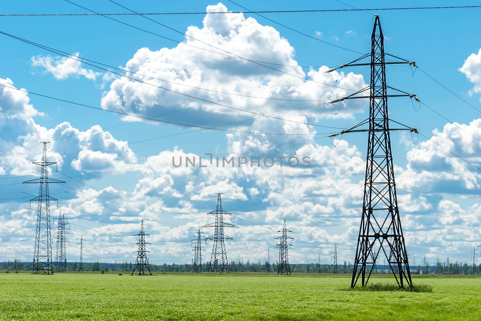 High voltage transmission tower lines on countryside in summer day