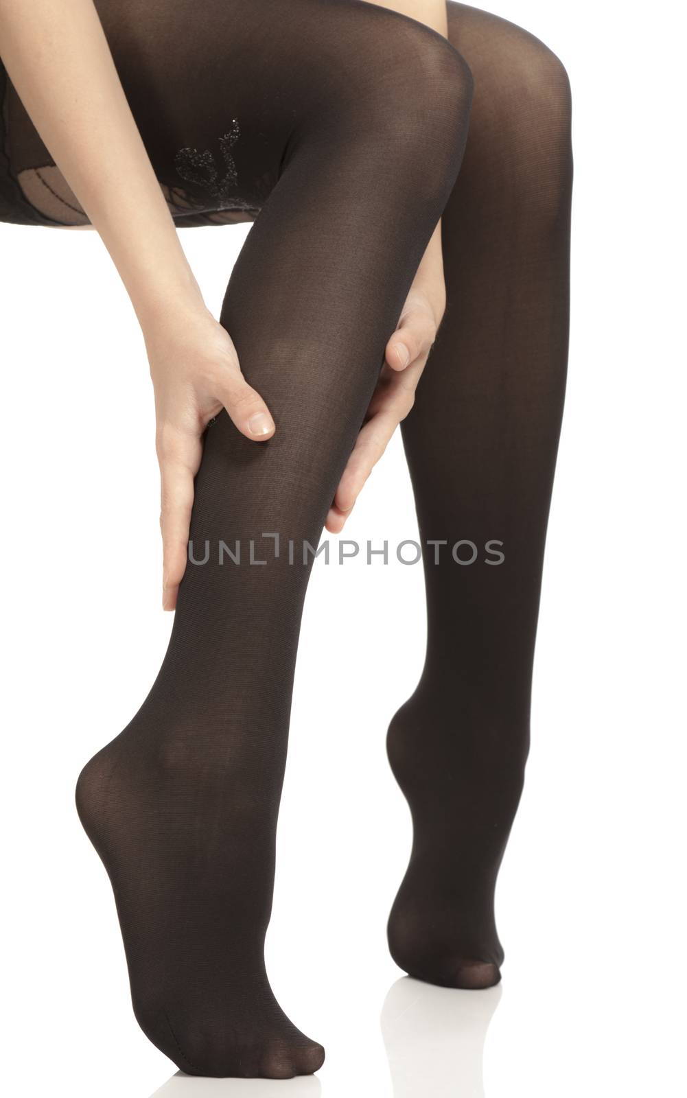 Close-up of female legs with pantyhose. Woman is rubbing her calf to relax pain.