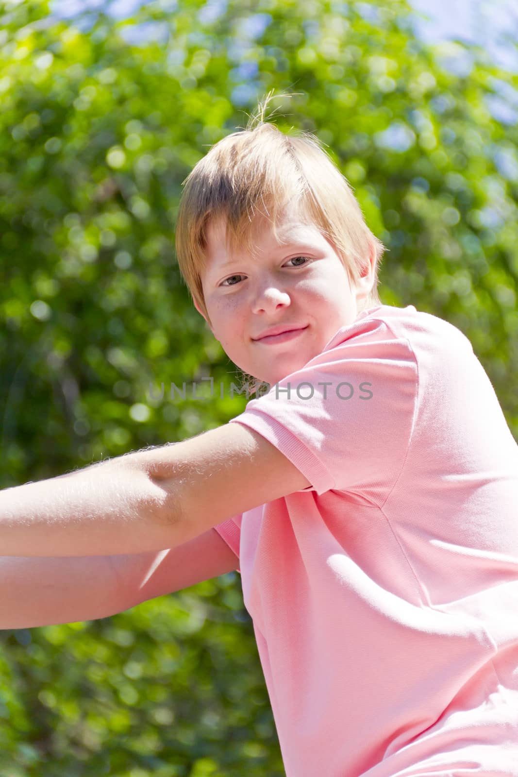 Smiling boy in pink shirt playing on stone wall