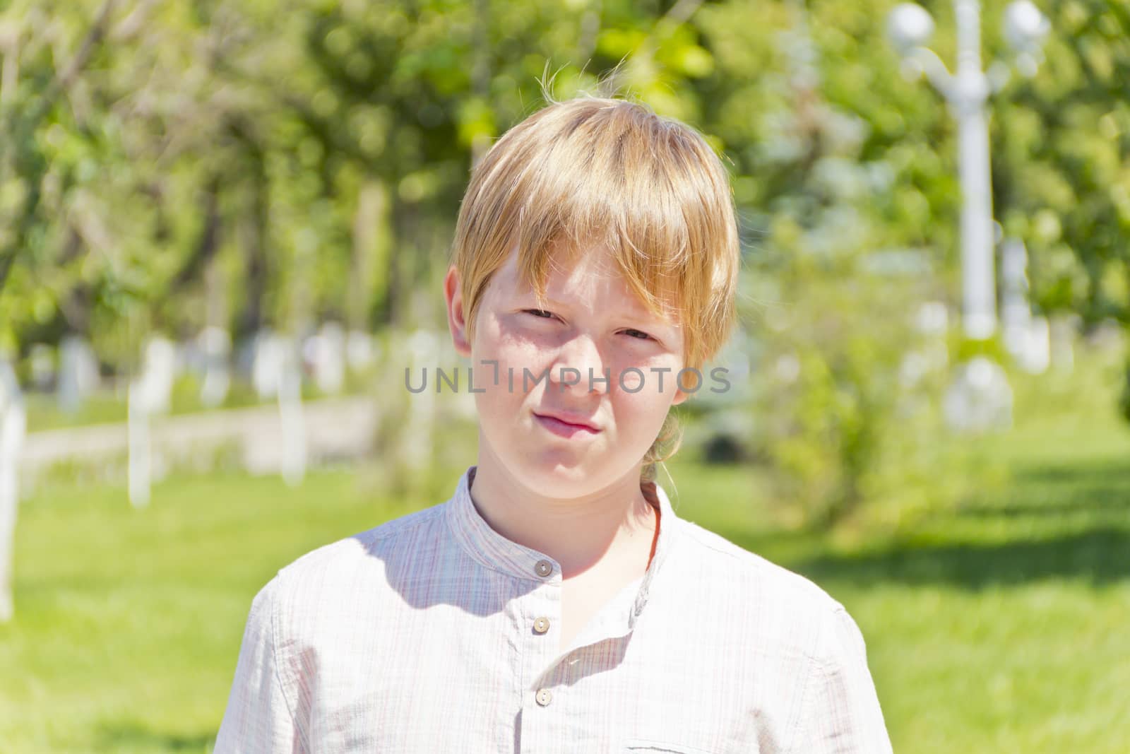Portrait of serious boy in park by Julialine