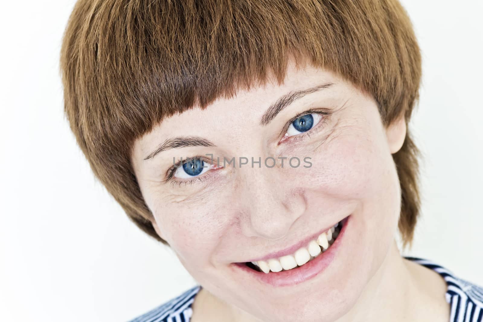 Smiling face of woman with red hair and blue eyes on white