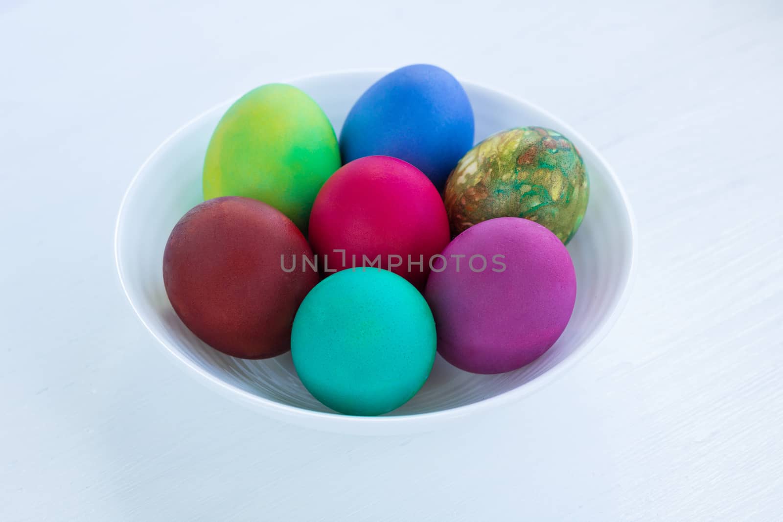 White plate of Easter multicolored boiled eggs decoration on wooden background