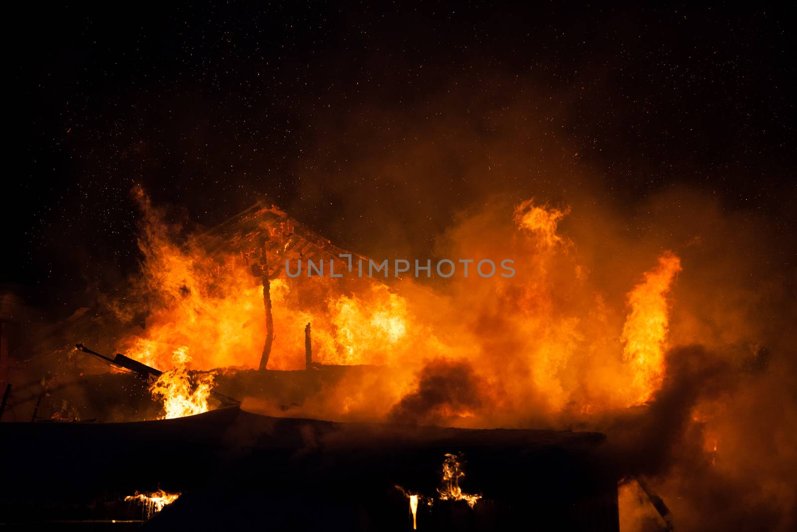 Arson or nature disaster - burning fire flame on wooden house roof