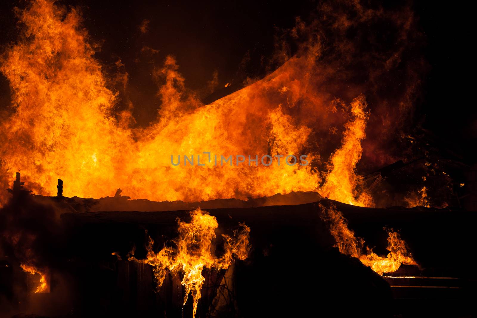 Arson or nature disaster - burning fire flame on wooden house roof