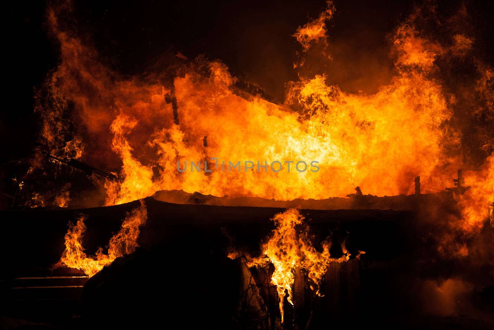 Arson or nature disaster - burning fire flame on wooden house roof