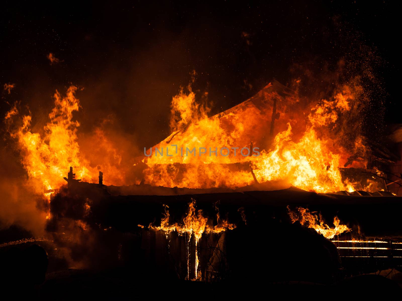 Burning fire flame on wooden house roof by ia_64