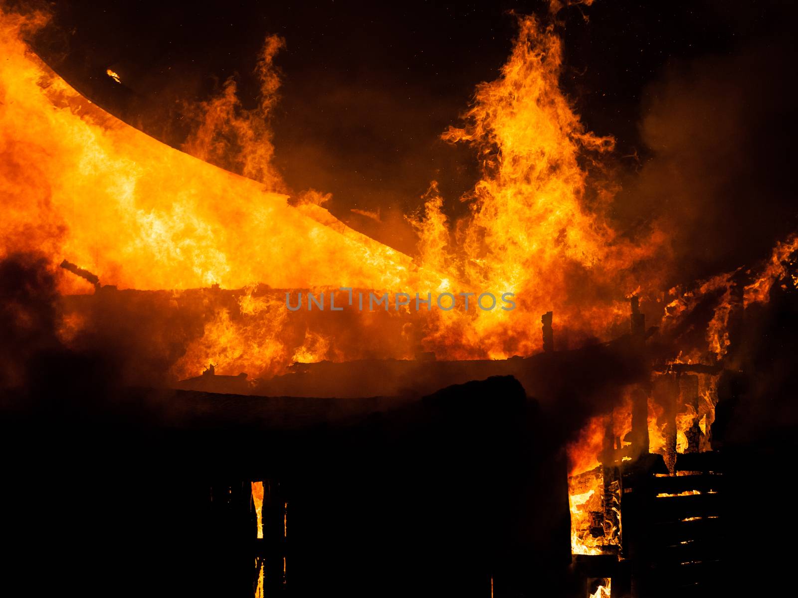 Burning fire flame on wooden house roof by ia_64