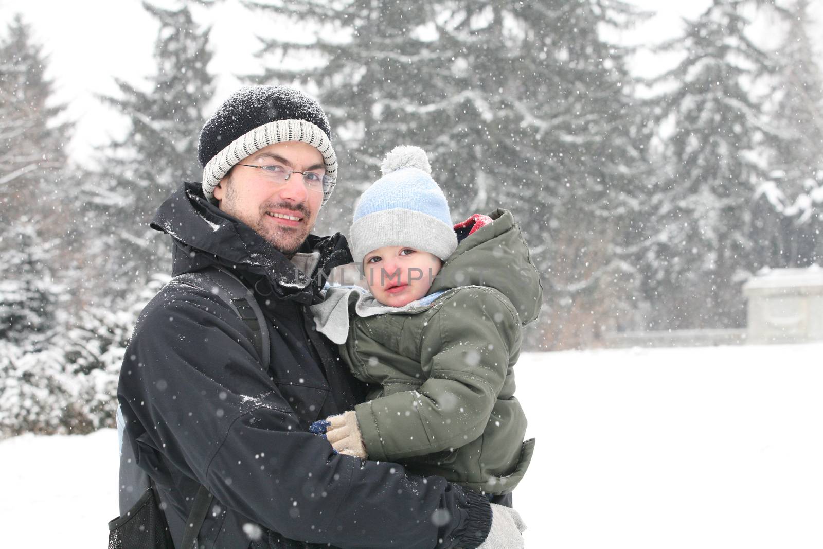 Portrait of an young father, carrying his offspring in a cold winter day.