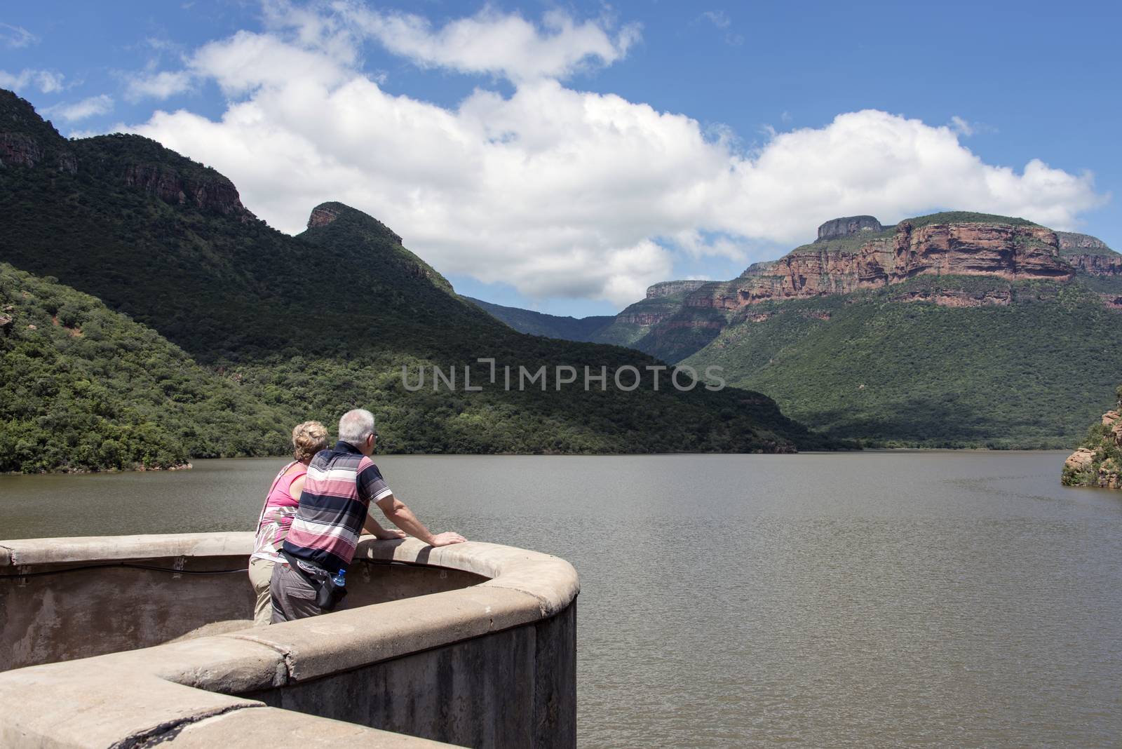 HOEDSPRUIT,SOUTH AFRICA,11-03-2014, Couple at the swadini dam and lake in south africa with the dragensbergen as background with rocks and green vegetation