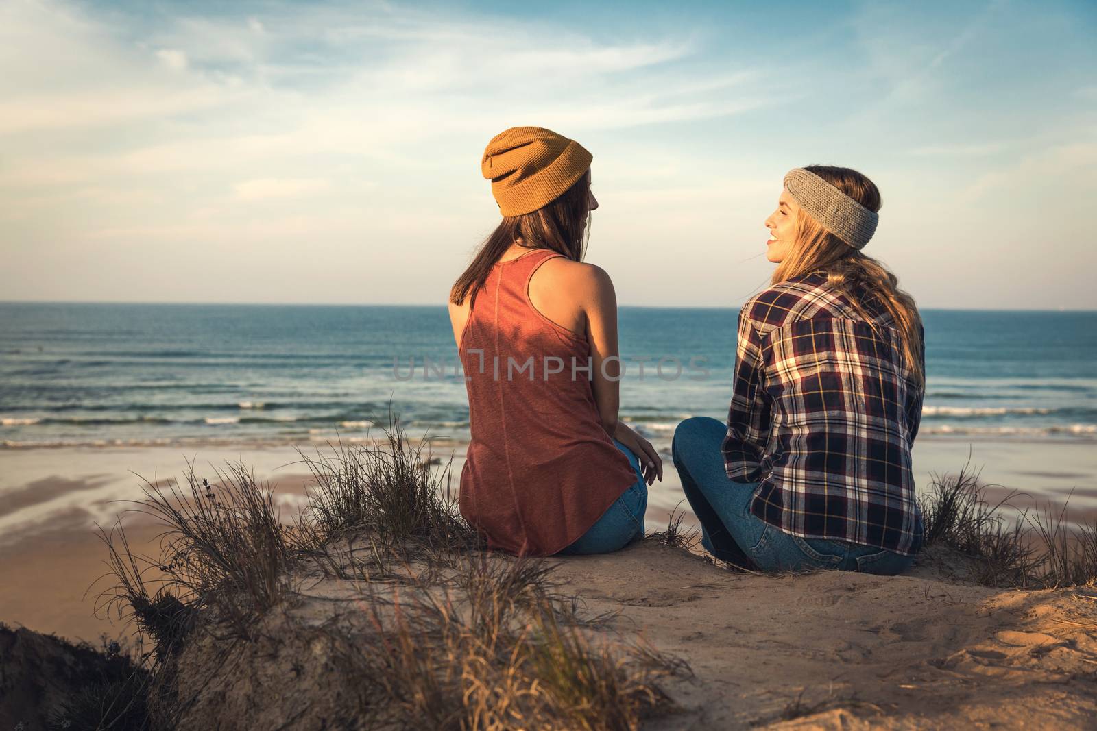 Two best friends sitting on the coastline having a good time